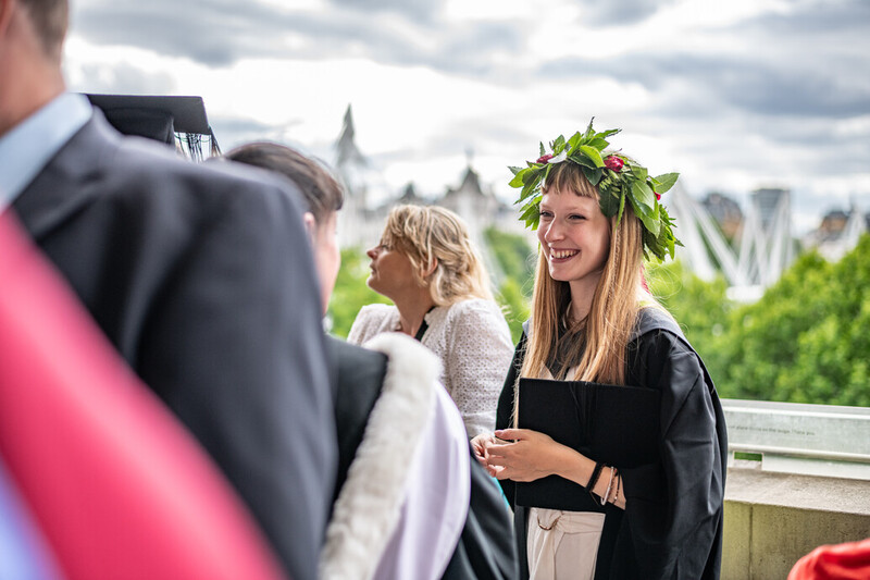 a graduating UCA student wears a flower garland instead of a traditional mortarboard cap