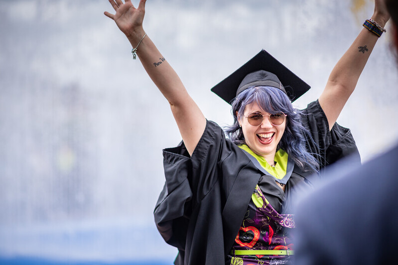 A UCA graduate cannot hide their excitement with arms aloft