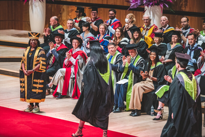 Students accept their awards on stage in front of honorary graduate Naomi Campbell