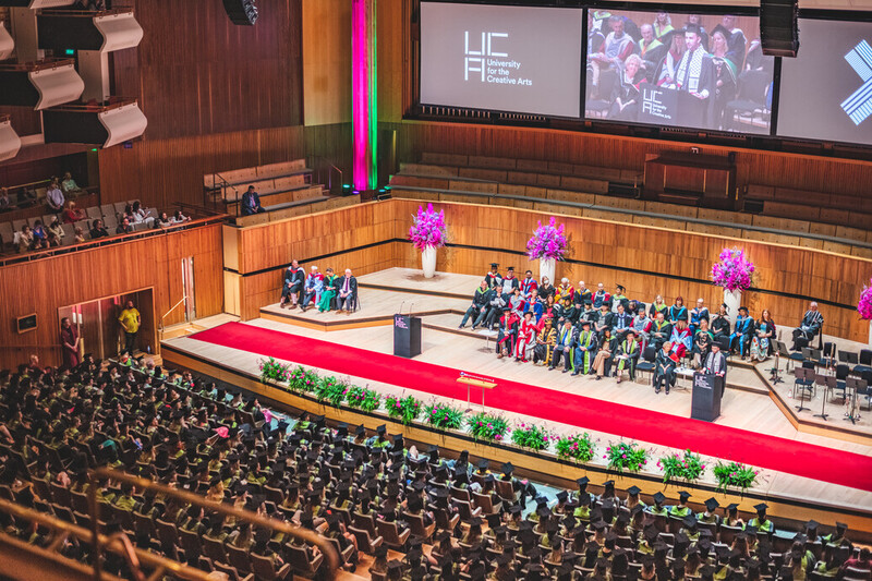 A wide shot of the graduation ceremony showing the full stage and audience