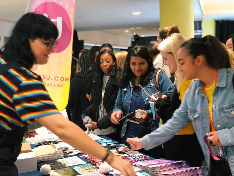 A group of new students pick up information and freebies from a stall at UCASU Freshers Week
