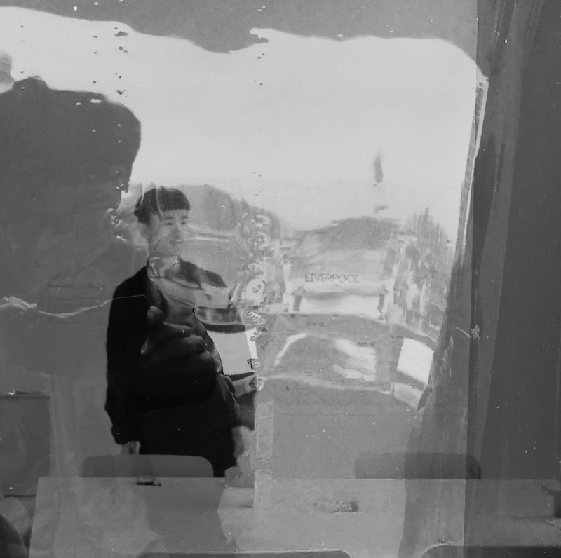 Black and white image shows Dr Zhuozhang Li, reflected on a window