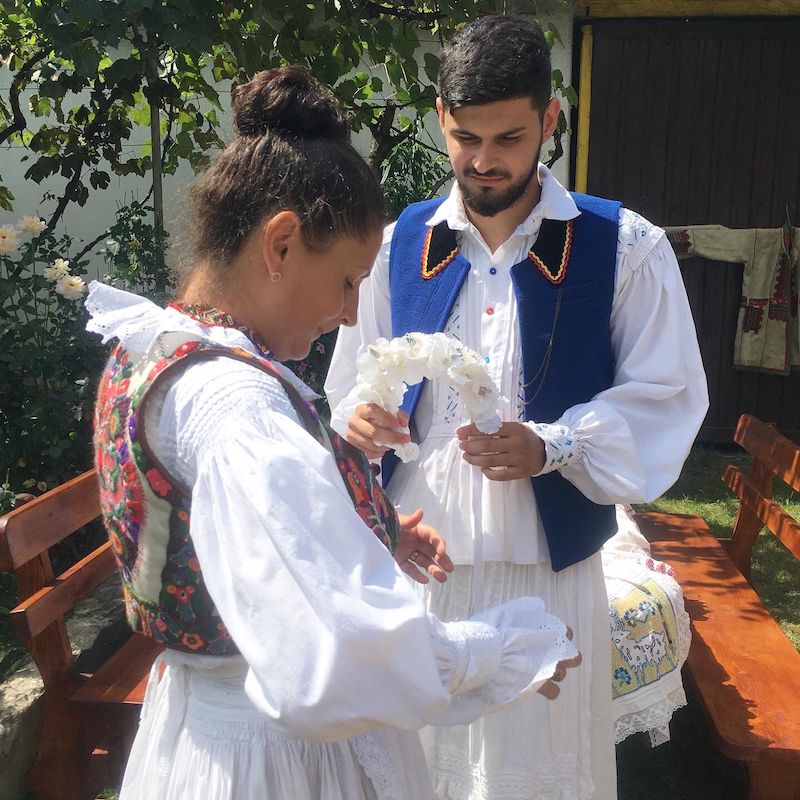 Razvan Fericean, a young artisan and custodian of tradition from Lunca village, Bihor,  helping his mother Adriana to dress up during a practical demonstration of the structure and functionality of the traditional clothing from his ethnographical region. Photo credit Andreea Tanasescu