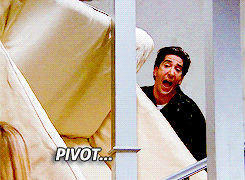 this moving gif image shows Ross from Friends trying to carry a sofa up the stairs - he's shouting 