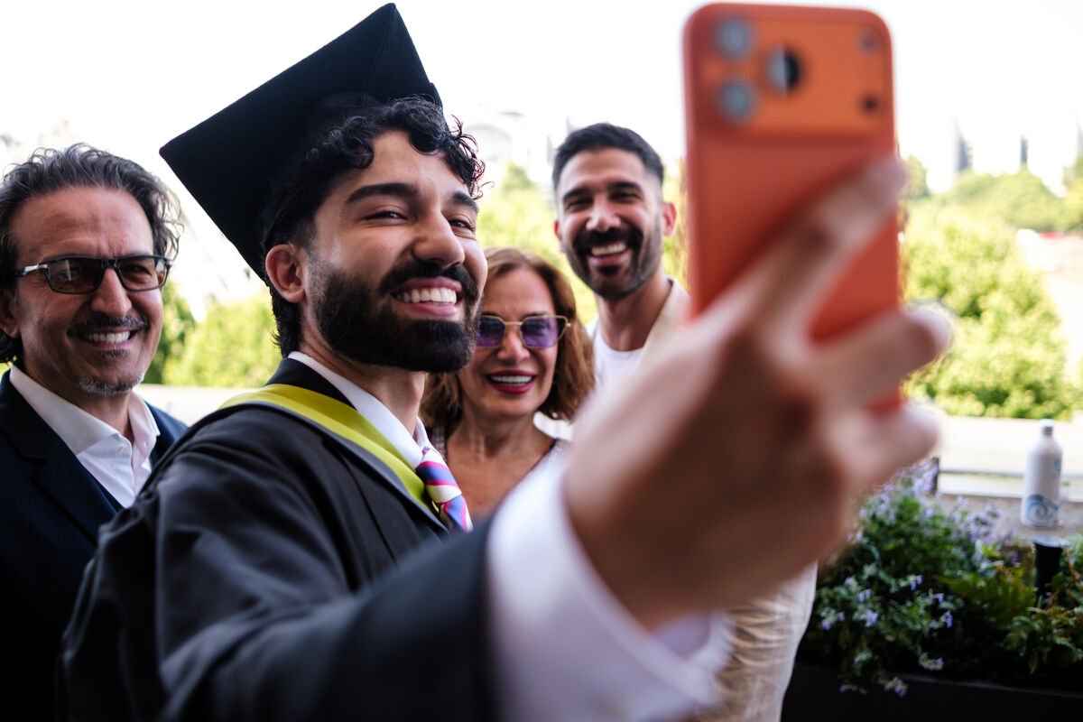 A UCA graduate taking a selfie in his robes alongside family members
