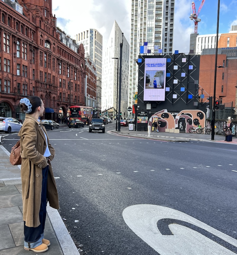 Olivia Cooper standing in front of the hoarding with her winning image at Old Street